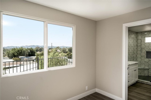 unfurnished bedroom featuring multiple windows, dark wood finished floors, baseboards, and a mountain view