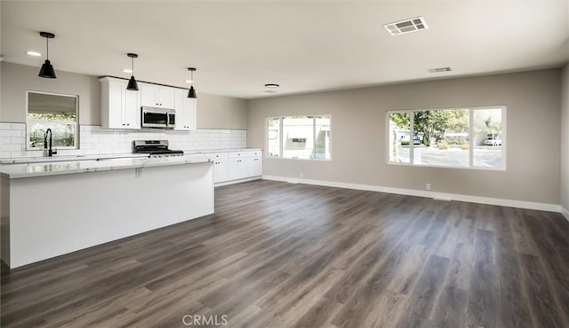 kitchen with light countertops, decorative backsplash, appliances with stainless steel finishes, a sink, and plenty of natural light