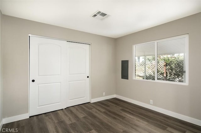 unfurnished bedroom with electric panel, visible vents, baseboards, and dark wood-style flooring