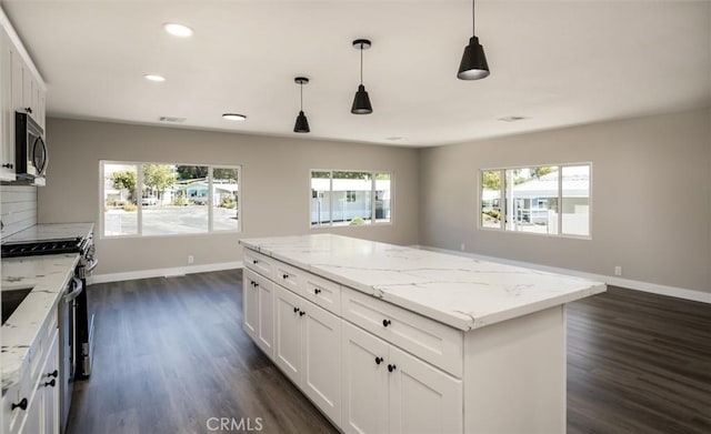 kitchen with a center island, dark wood finished floors, appliances with stainless steel finishes, white cabinets, and baseboards