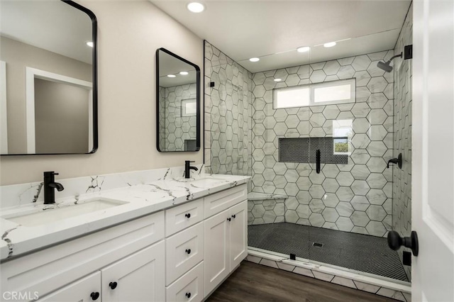 full bathroom featuring recessed lighting, tiled shower, a sink, and double vanity