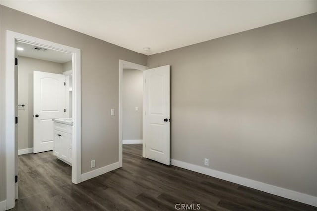 unfurnished bedroom with dark wood-style flooring, visible vents, and baseboards