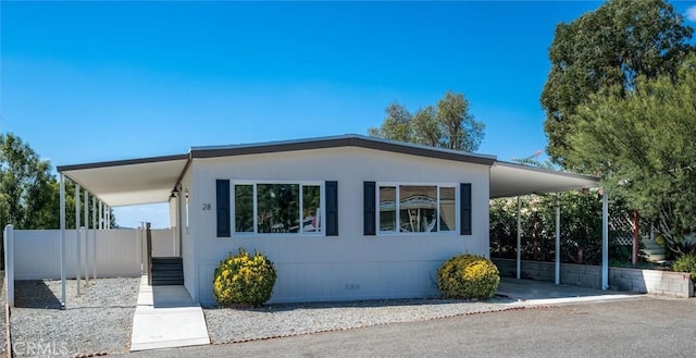 view of front facade with a carport, crawl space, driveway, and fence