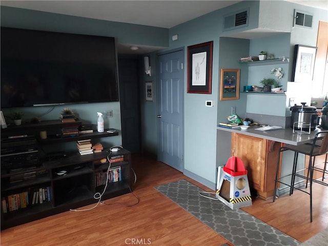 living area featuring baseboards, visible vents, and wood finished floors