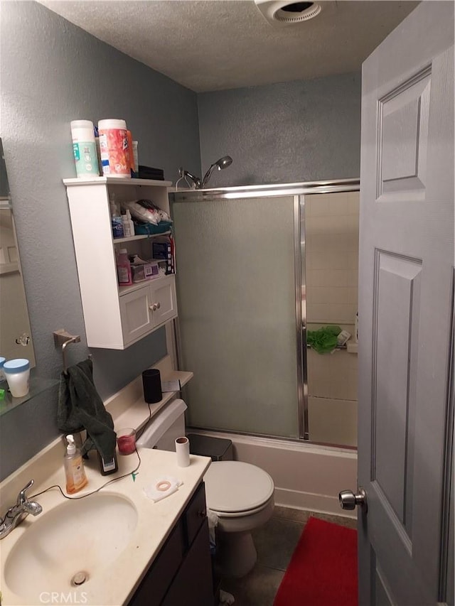 bathroom with a textured wall, toilet, enclosed tub / shower combo, tile patterned floors, and a textured ceiling