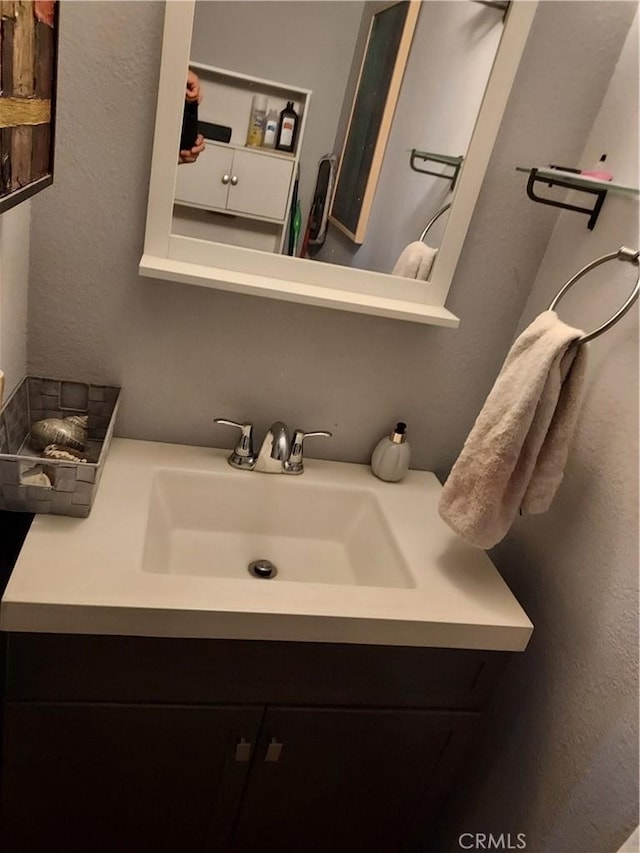 bathroom featuring a textured wall and vanity