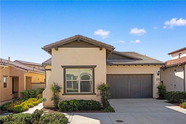 view of front of property featuring concrete driveway, an attached garage, a tile roof, and stucco siding