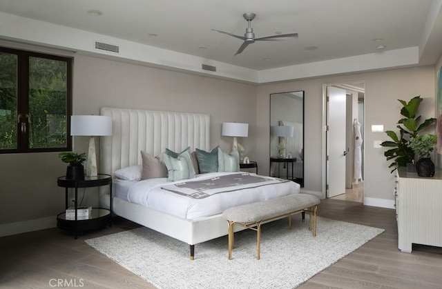 bedroom with wood finished floors, visible vents, and baseboards