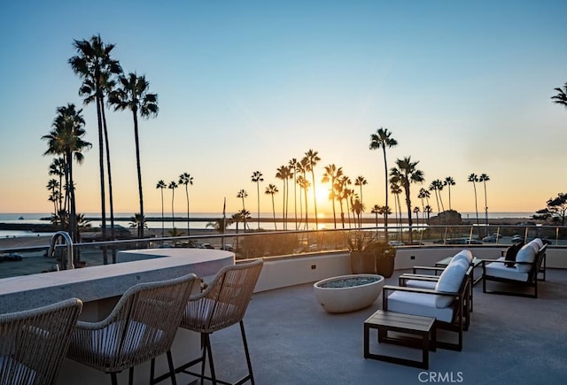 patio terrace at dusk featuring a water view and a fire pit