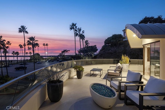 patio terrace at dusk with an outdoor hangout area and a balcony