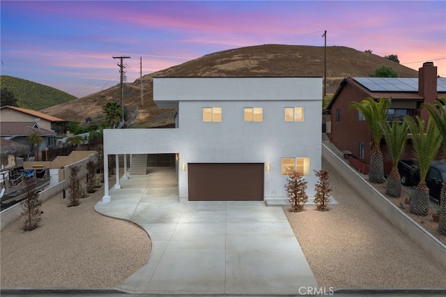 contemporary home with a garage, a carport, driveway, and fence