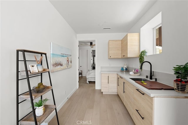 kitchen with visible vents, light brown cabinets, light countertops, and a sink