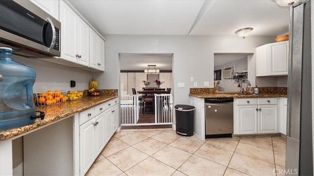 kitchen with light tile patterned floors, appliances with stainless steel finishes, a sink, and white cabinetry