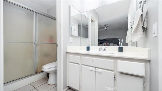 bathroom featuring toilet, ceiling fan, tile patterned floors, vanity, and a shower stall