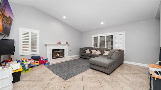 living area with lofted ceiling, a brick fireplace, baseboards, and light tile patterned floors