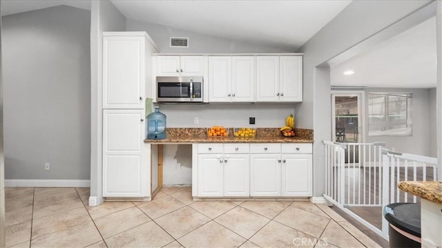 kitchen featuring lofted ceiling, white cabinetry, visible vents, and stainless steel microwave