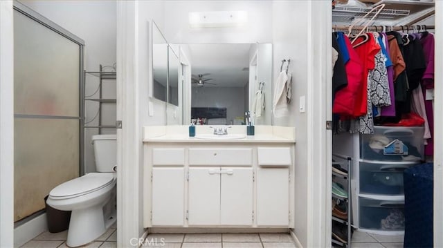 bathroom featuring ceiling fan, toilet, vanity, tile patterned floors, and a stall shower