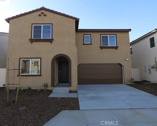 mediterranean / spanish home with concrete driveway, an attached garage, a tile roof, and stucco siding