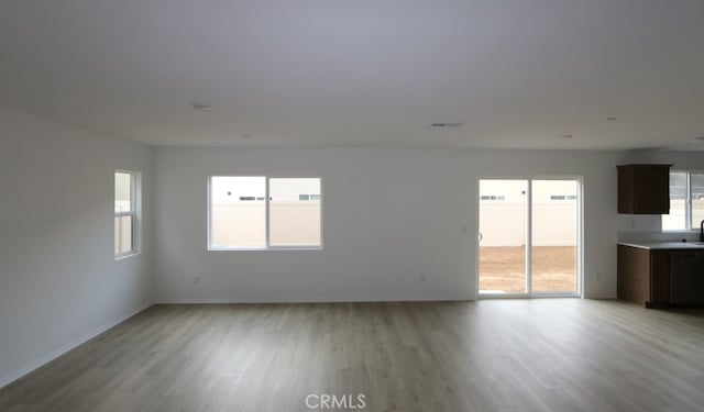 unfurnished living room with light wood-style floors and baseboards