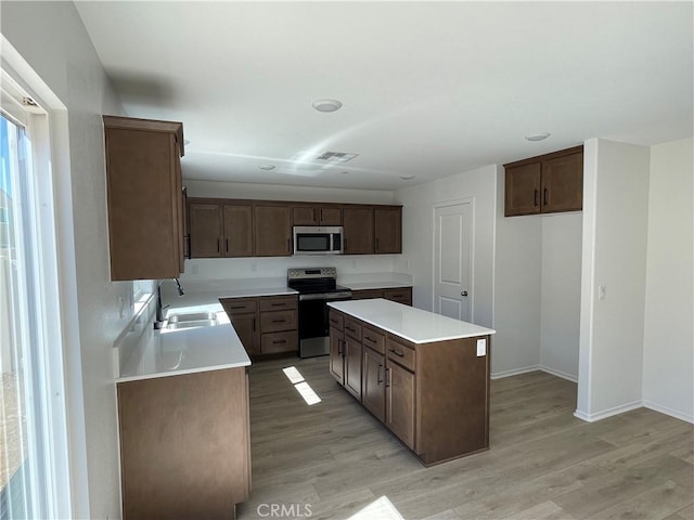 kitchen featuring appliances with stainless steel finishes, light wood-style flooring, a sink, and visible vents