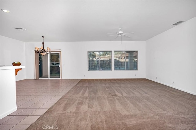 carpeted empty room with tile patterned flooring, visible vents, and ceiling fan with notable chandelier