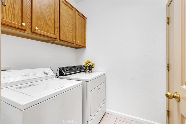 washroom with cabinet space, light tile patterned floors, baseboards, and separate washer and dryer