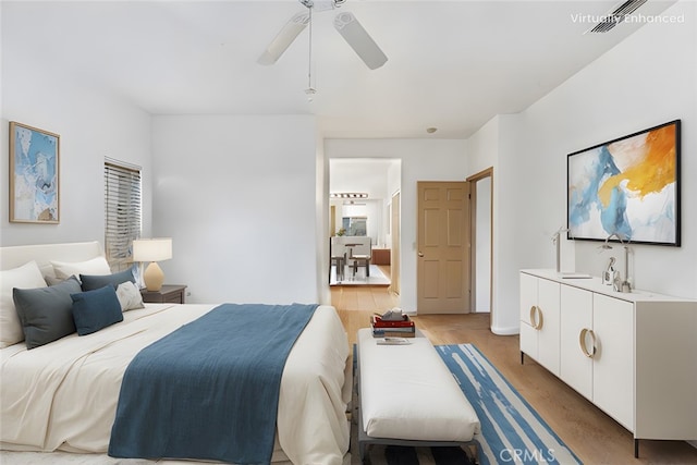 bedroom featuring light wood finished floors, visible vents, and a ceiling fan