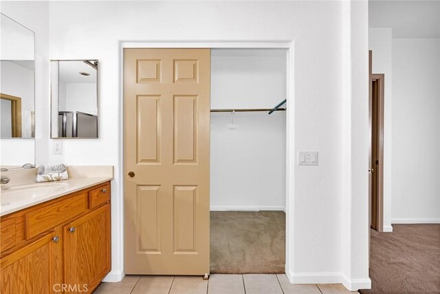 bathroom featuring a spacious closet, tile patterned flooring, vanity, and baseboards