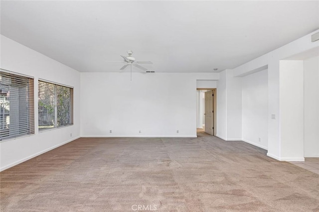 carpeted spare room with ceiling fan and baseboards