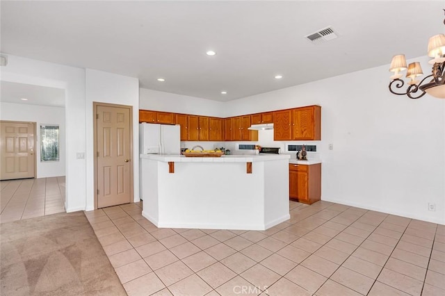 kitchen with light tile patterned floors, recessed lighting, under cabinet range hood, visible vents, and white fridge with ice dispenser