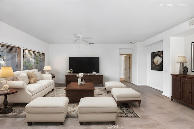 living area with a ceiling fan, light colored carpet, and baseboards