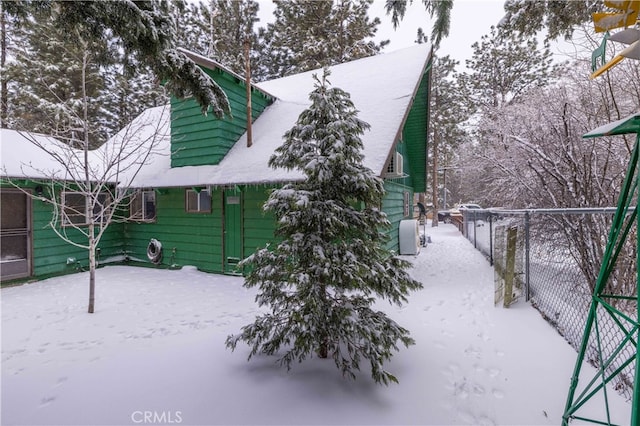 snow covered back of property featuring fence