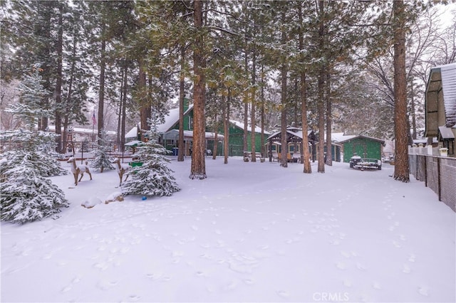 snowy yard featuring a playground and fence