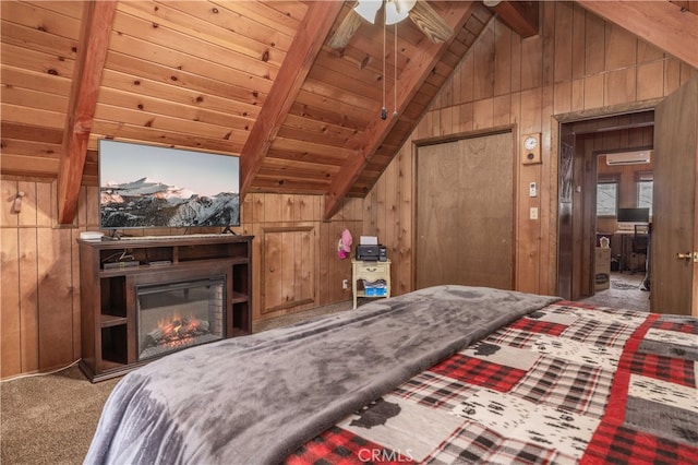 carpeted bedroom featuring vaulted ceiling with beams, wood walls, a glass covered fireplace, and wood ceiling