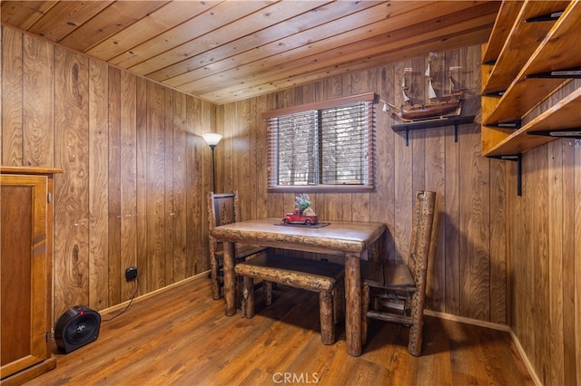 dining room featuring baseboards, wooden ceiling, wood finished floors, and wooden walls