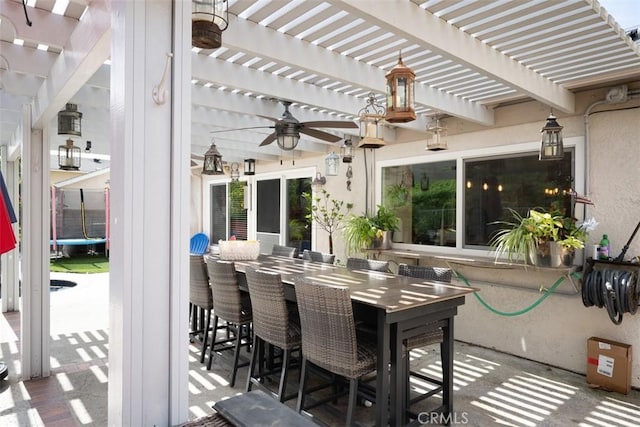 view of patio / terrace featuring a trampoline, ceiling fan, outdoor dining space, and a pergola