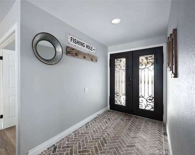 entryway with french doors, brick floor, and baseboards