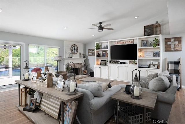 living room featuring light wood finished floors, recessed lighting, a fireplace, ceiling fan, and vaulted ceiling