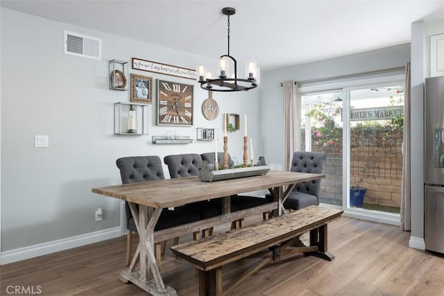 dining space featuring a notable chandelier, baseboards, visible vents, and light wood-type flooring