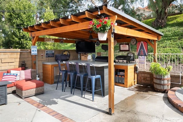 view of patio / terrace with outdoor wet bar, fence, and an outdoor kitchen