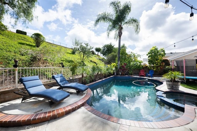 view of swimming pool with a patio area, a trampoline, a fenced backyard, and a pool with connected hot tub