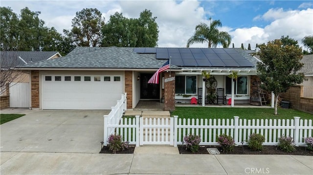 view of front of property with driveway, roof with shingles, solar panels, a garage, and a fenced front yard