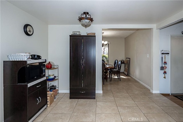 kitchen with a chandelier, light tile patterned flooring, and baseboards