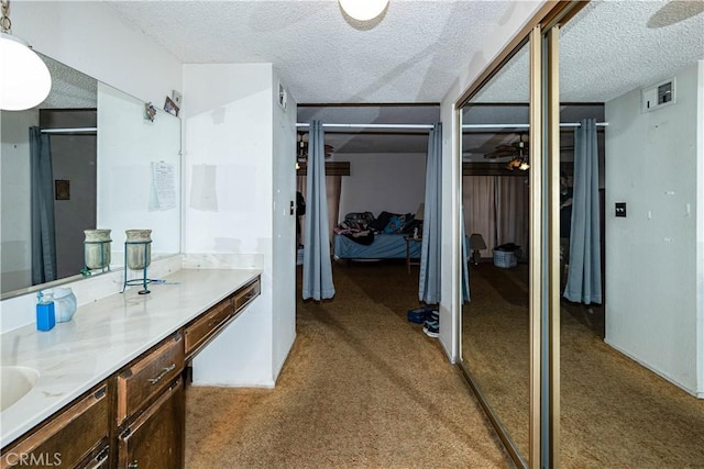 bathroom with carpet floors, visible vents, a textured ceiling, and vanity