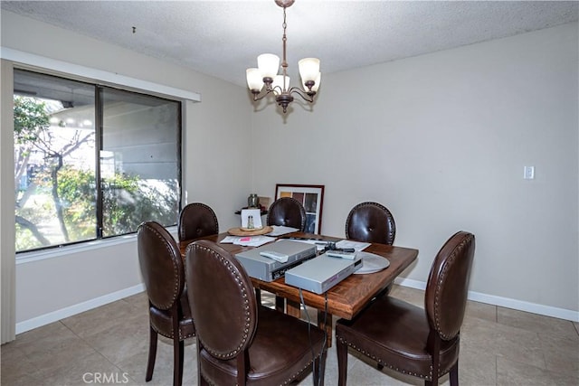 dining room with an inviting chandelier, baseboards, and a textured ceiling