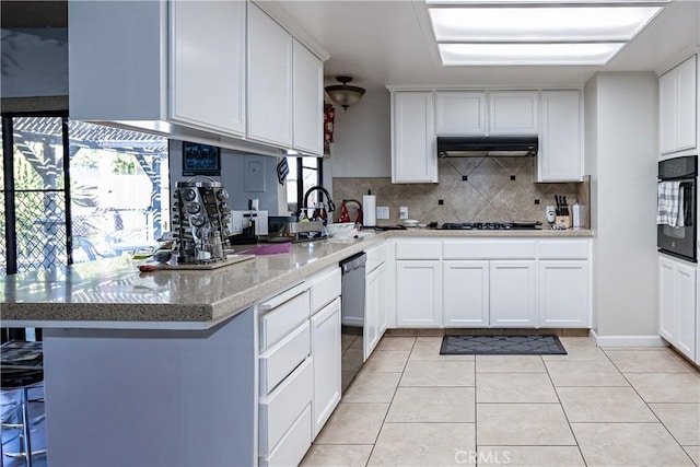 kitchen with light tile patterned floors, under cabinet range hood, black oven, decorative backsplash, and dishwasher