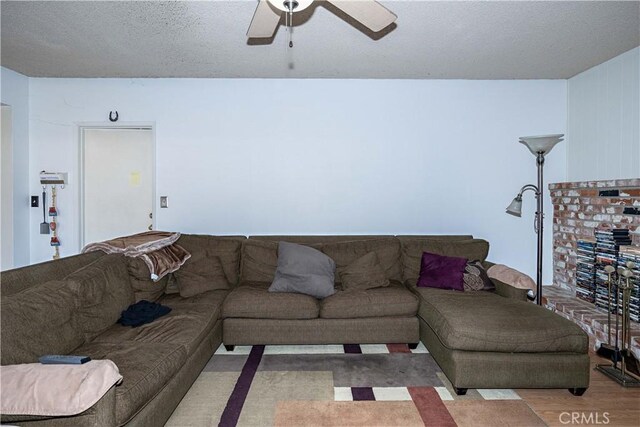 living area featuring a ceiling fan, a textured ceiling, and wood finished floors