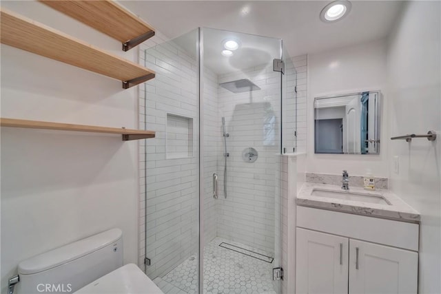 bathroom featuring toilet, a shower stall, recessed lighting, and vanity