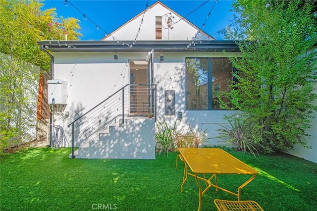 rear view of house featuring stucco siding and a yard