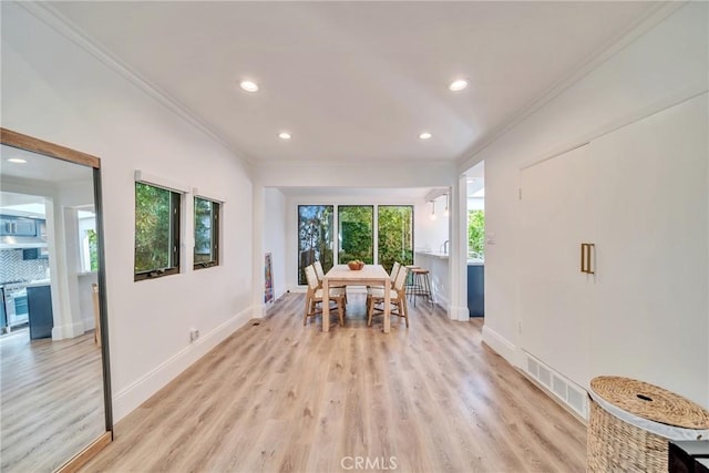 dining space with baseboards, visible vents, crown molding, and light wood finished floors